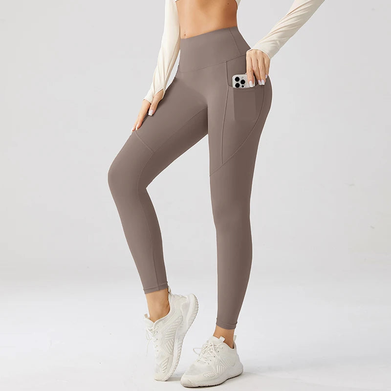 Person wearing brown leggings with a pocket on a light gray background